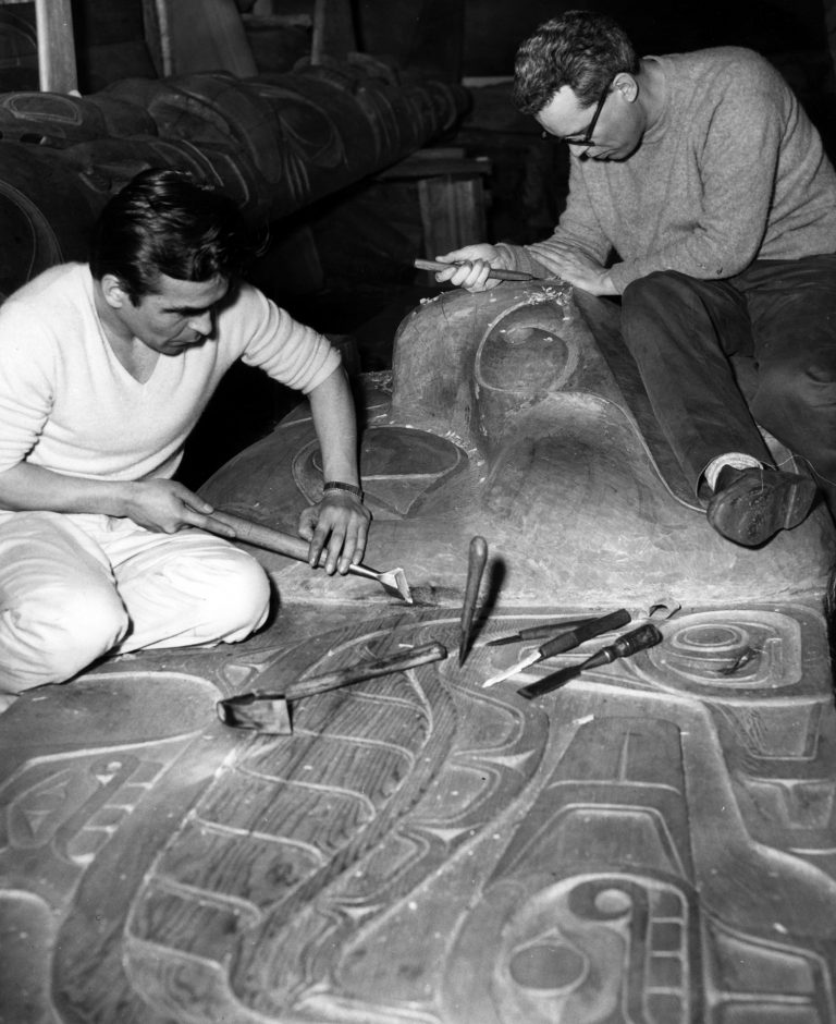 Bill Reid and Douglas Cranmer carving the frontal board of the Haida mortuary pole for Totem Park in 1961